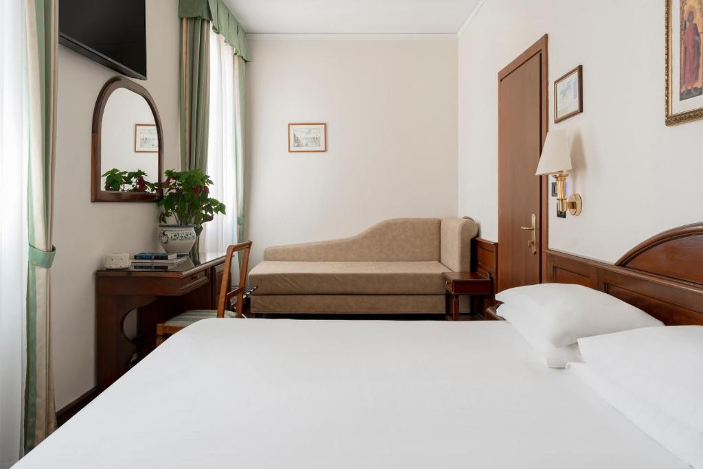a hotel room with two beds and a chair at Hotel Boccaccio in Florence