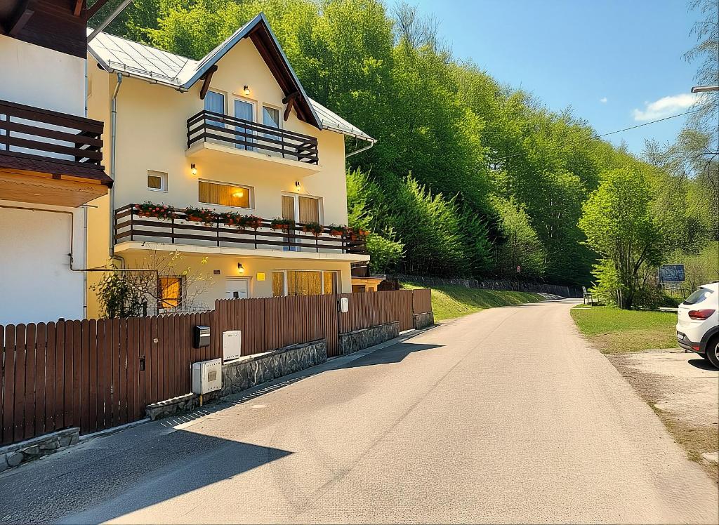 a house on a road with a fence at Casa Sonne Bușteni in Buşteni