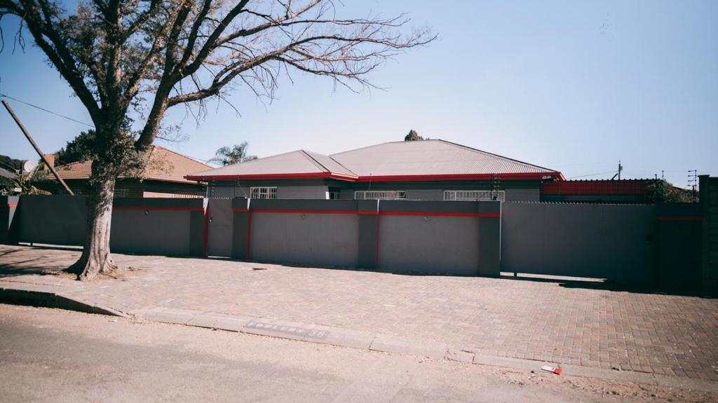 a house with a fence and a tree in front of it at Lodge36 in Vanderbijlpark