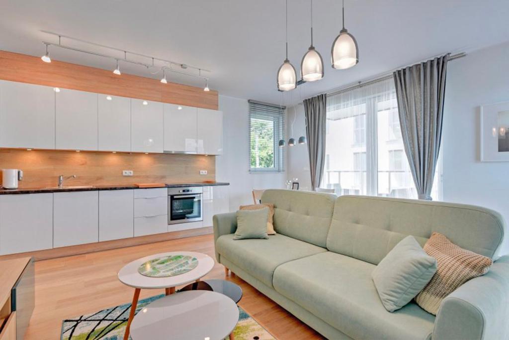 a living room with a couch and a kitchen at Flatbook - Seaside Apartments Tre Mare II in Gdańsk