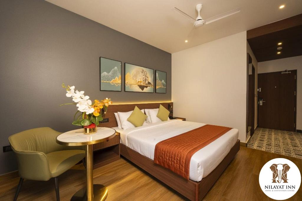 a bedroom with a bed and a table and a chair at Nilayat Inn in Ollūr