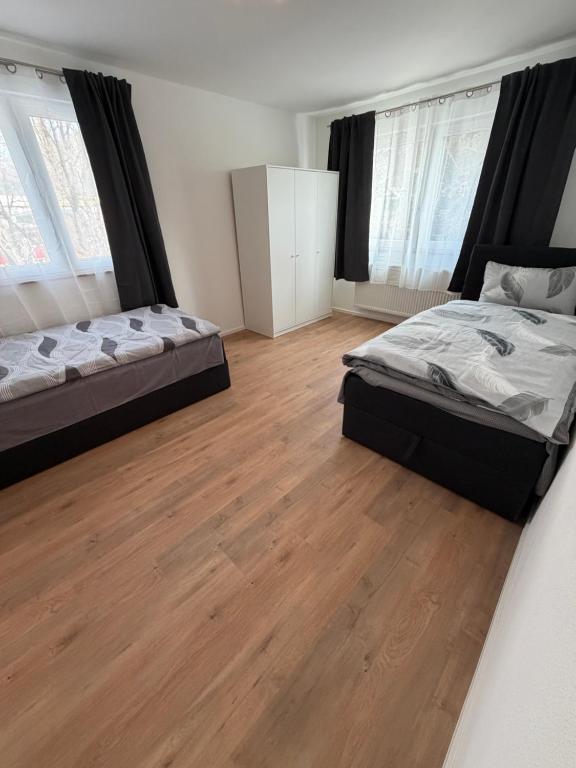 two beds in a room with wooden floors and windows at Ferienhaus Fünf Täler in Geislingen an der Steige
