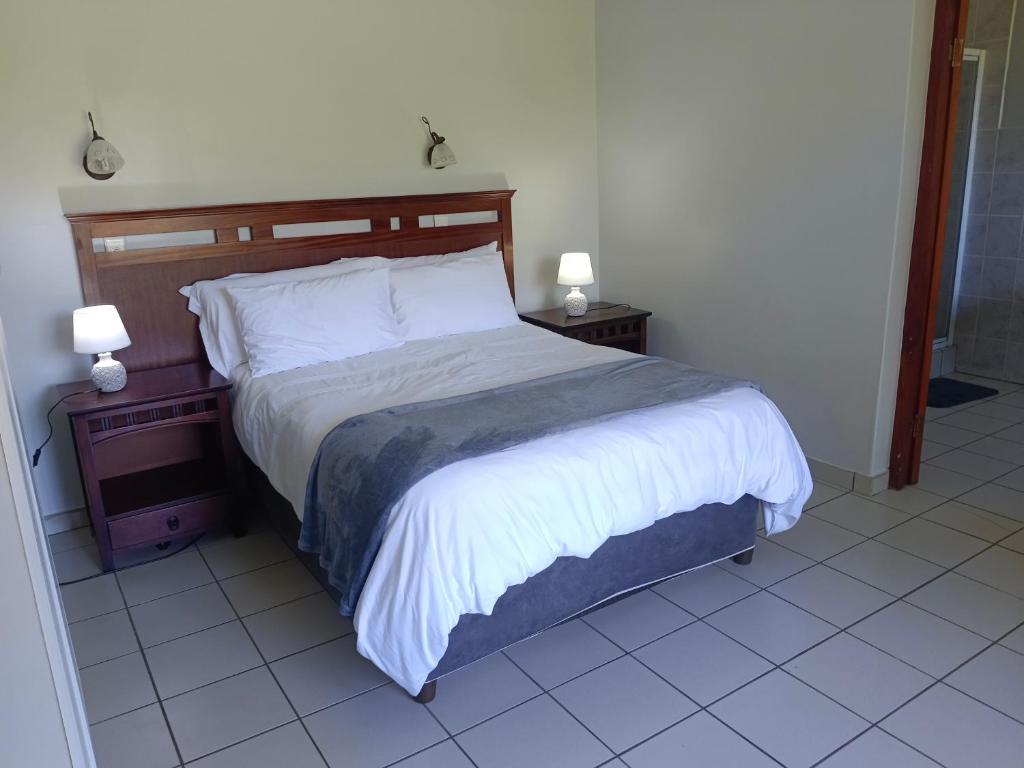 a bed in a bedroom with two nightstands and two lamps at Eagles Lodge One in Vosburg