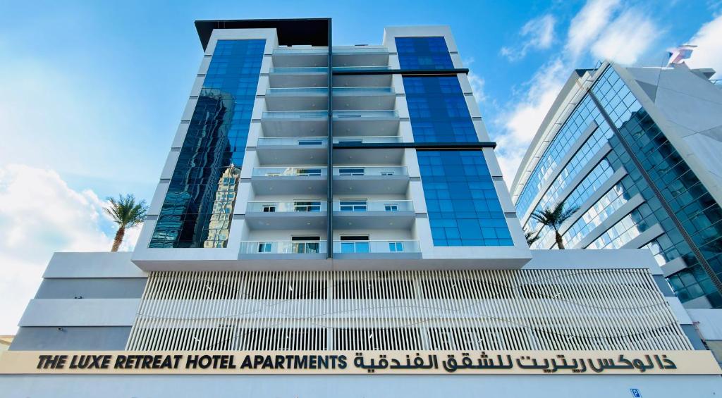 a tall building with a sign in front of it at The Luxe Retreat Hotel Apartments in Dubai
