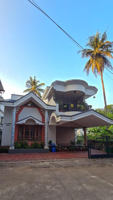a house with a palm tree in front of it at Spacious 3-Bedroom Private Villa in Mangalore - Ideal Getaway for Family and Friends in Mangalore