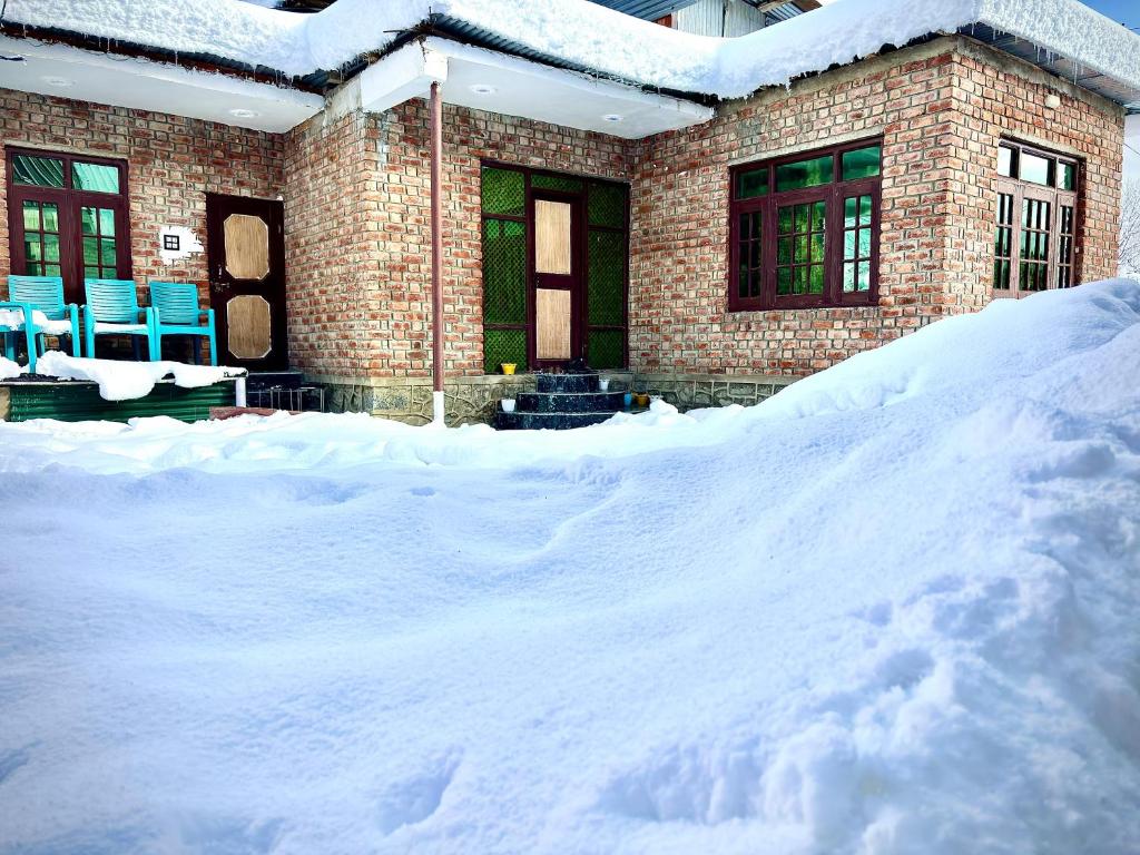 a house with a pile of snow in front of it at Pine Guest House sawan tangmarg in Tangmarg