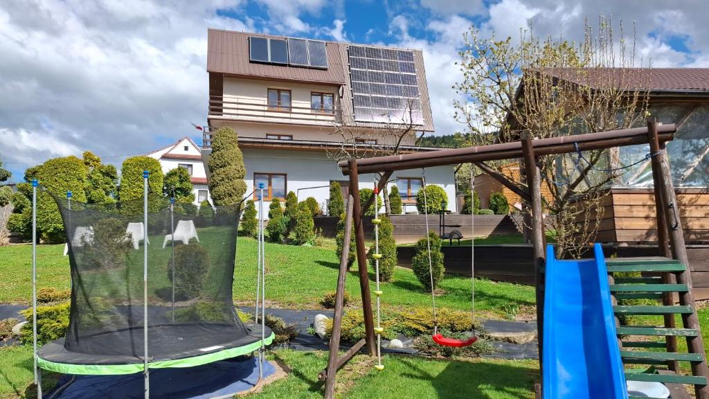 ein Spielplatz in einem Garten mit einem Haus in der Unterkunft Agrorelax - Studio - Domek - Pokój in Kasina Wielka