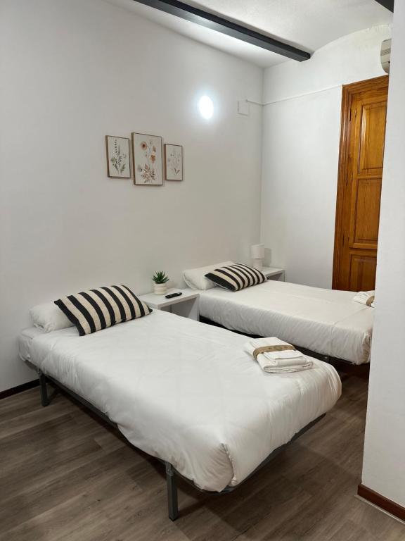 three beds in a room with white walls and wooden floors at Mini Peixcateria A in Sagunto