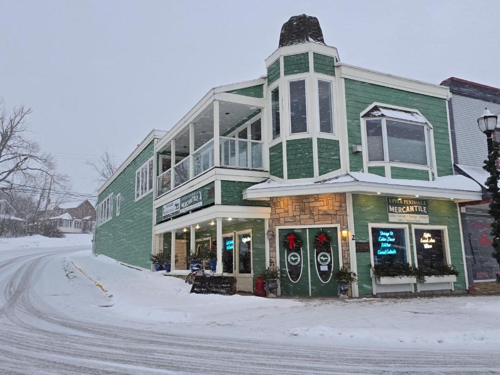a green and white building on a snowy street at Pier Harbor #1 in Saint Ignace