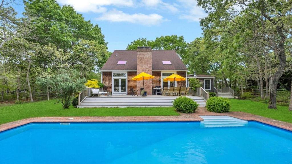 a home with a swimming pool in front of a house at Villa Willow & Waves in East Hampton