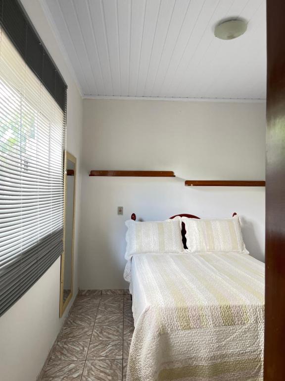 a bedroom with a bed with white sheets and a window at Raízes do Cerrado in Cavalcante