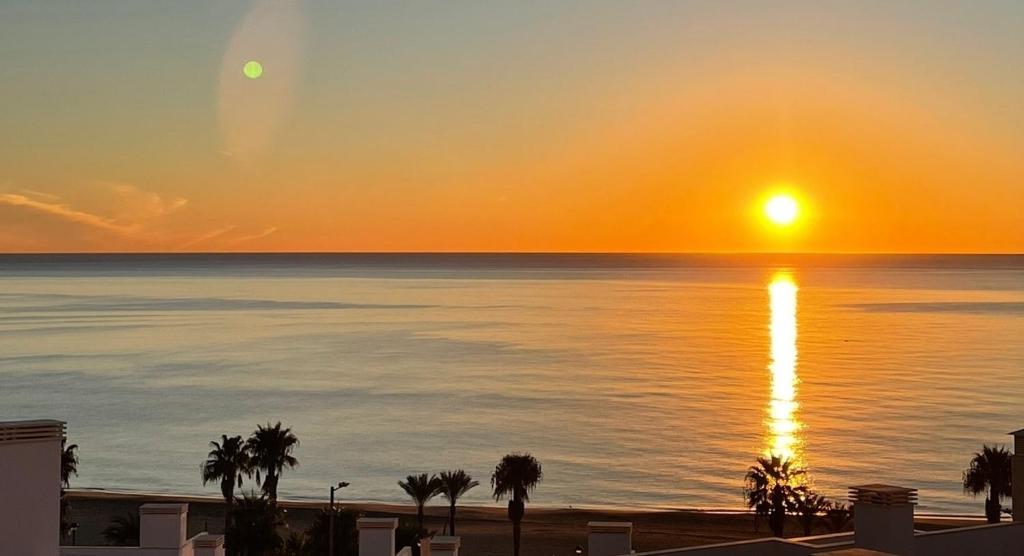 a sunset over the ocean with palm trees on the beach at Penthouse Mojacar beach newly build in Mojácar
