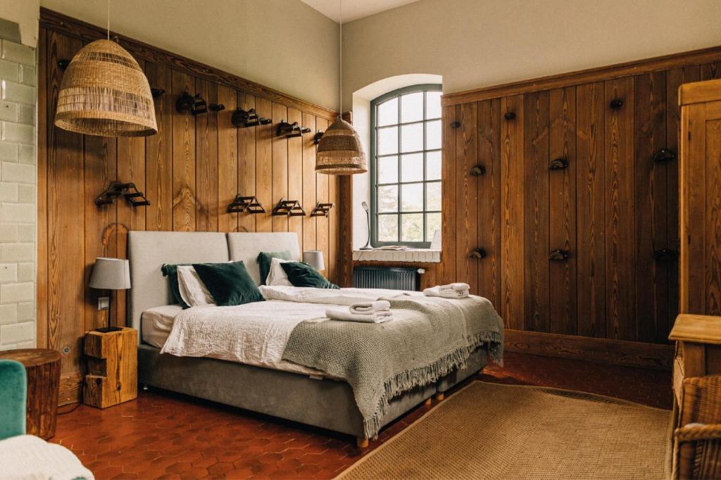 a bedroom with a bed with wooden walls and a window at Folwark Wąsowo in Wąsowo