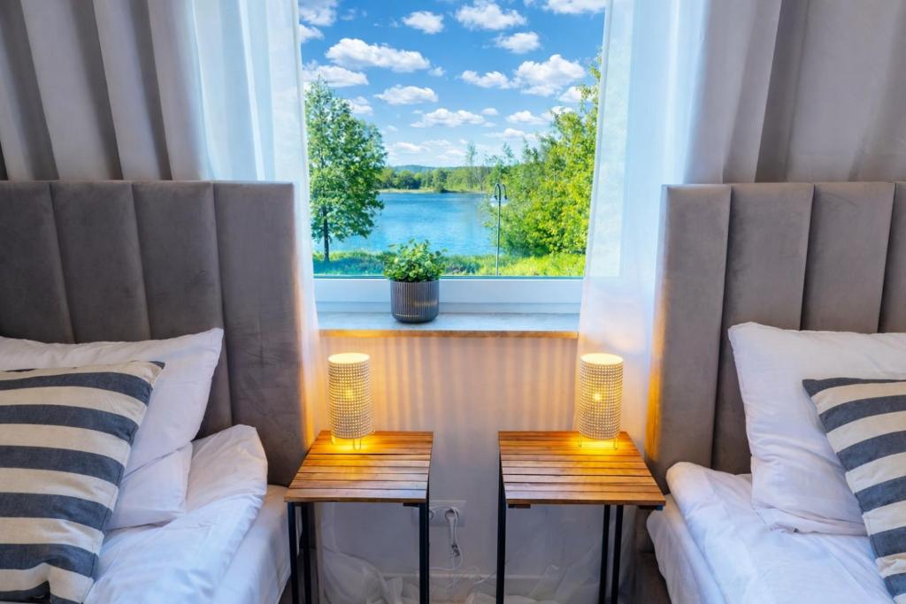 a room with two beds and a window with a view at Unique View Apartment - 3pok, 4 łóżka, widok na rzekę, centrum, Netflix, parking, winda in Iława