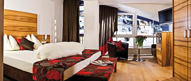 a hotel room with a bed and a chair at Sporthotel Snowwhite in Obertauern