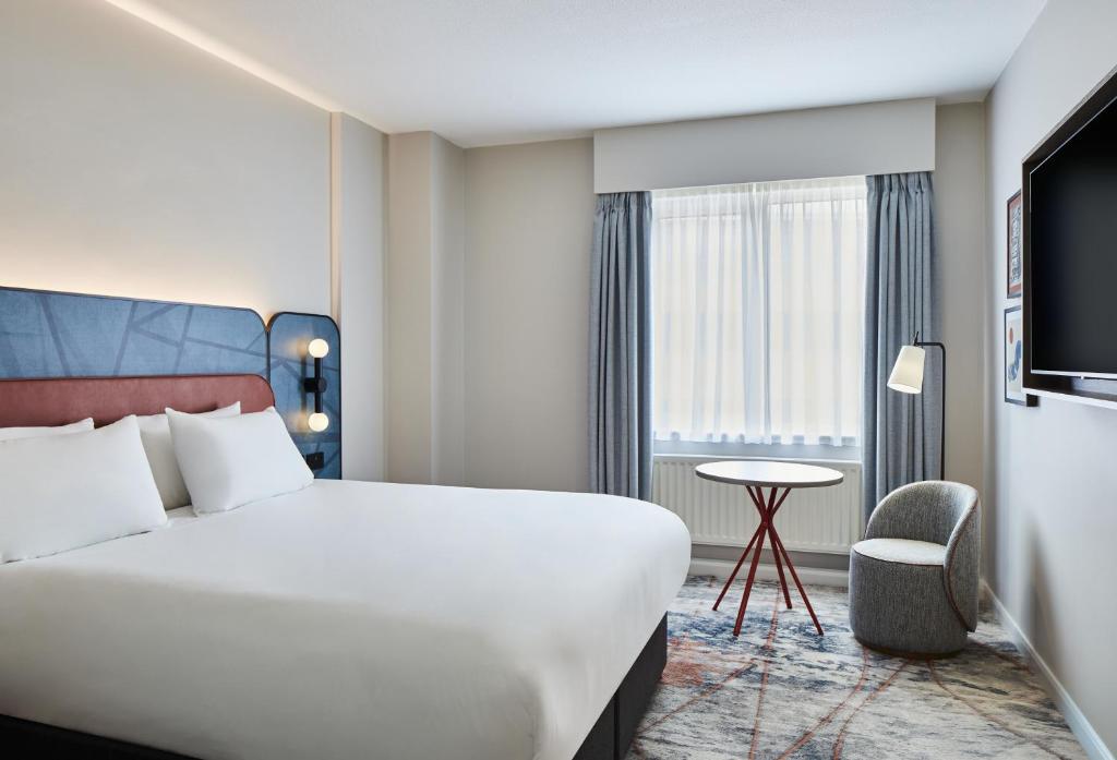 a hotel room with a bed and a chair and a window at Leonardo Hotel Newcastle in Newcastle upon Tyne