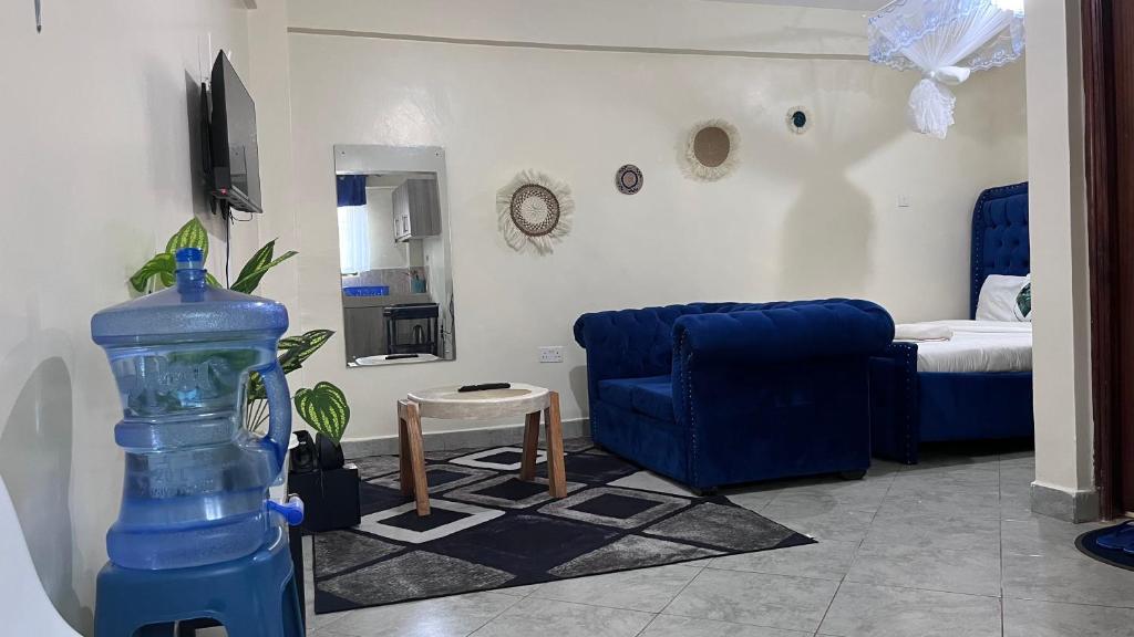 a living room with a blue chair and a bedroom at Emerald Tulivu Place in Ruaka