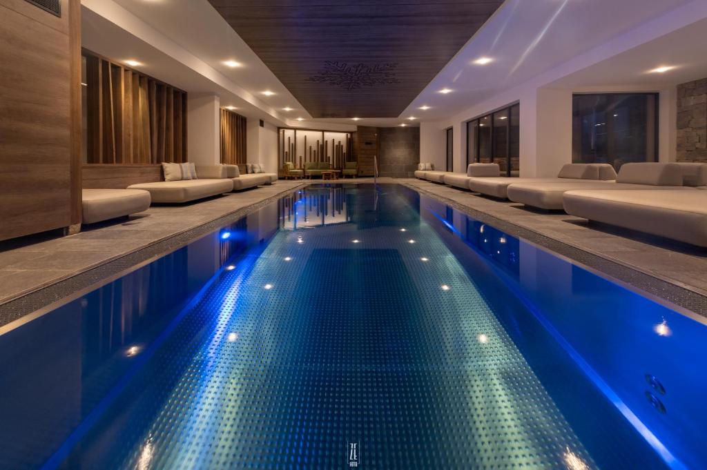 a swimming pool with blue lights in a hotel at Chalet Hôtel & Spa Le Collet in Xonrupt-Longemer