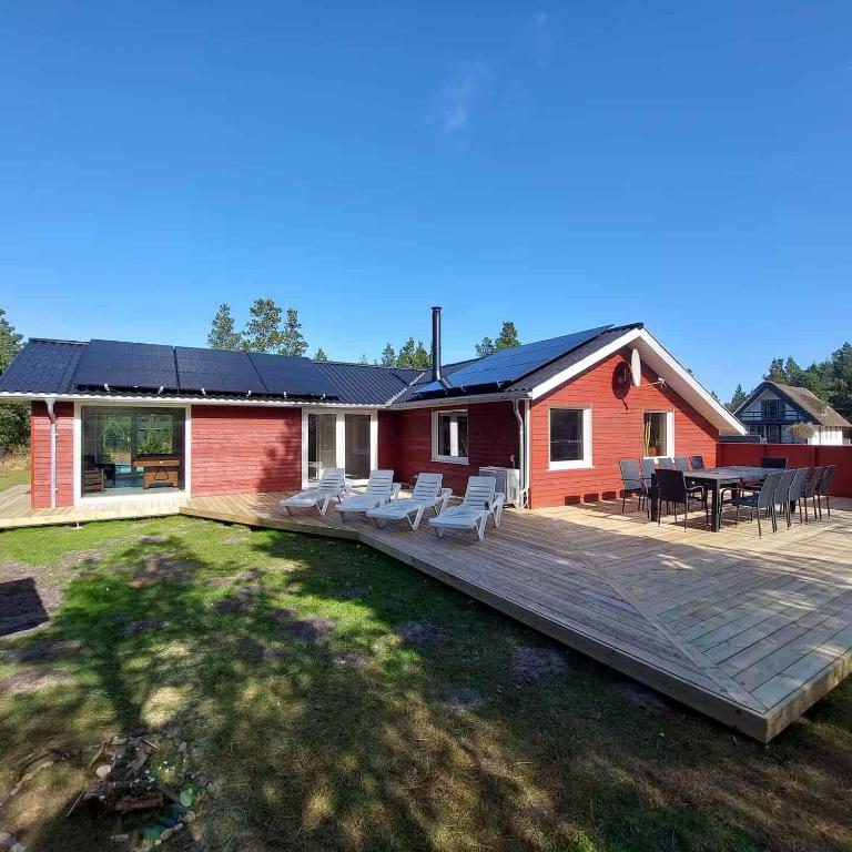 a house with a wooden deck with chairs and a table at Spacious Holiday Home With Spa Forest in Høm