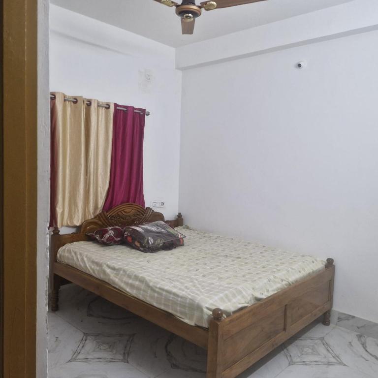 a small bed in a room with curtains at shreejikunj in Bolpur