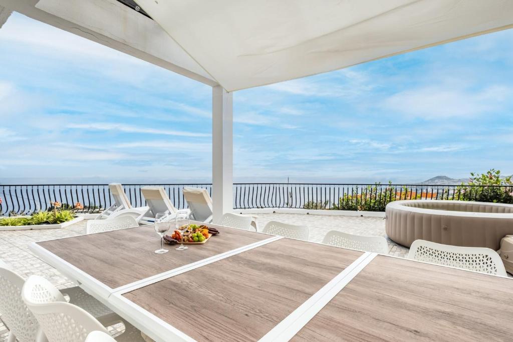 a table and chairs on a patio with a view of the ocean at Villa Amor Do Mar -180° Sea View, Jacuzzi,Terrace in Funchal