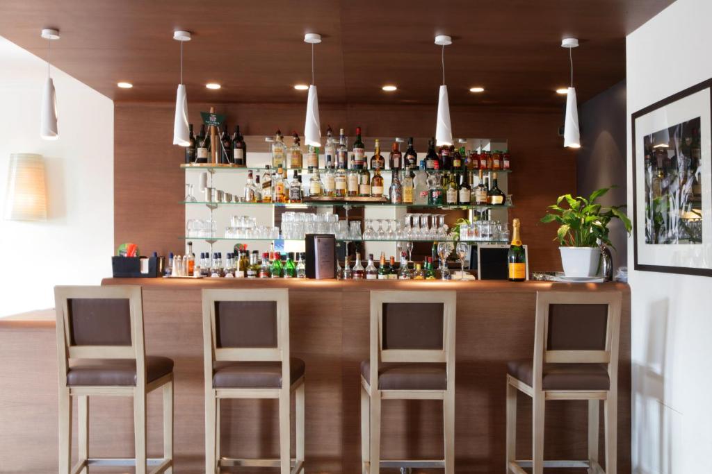 a bar in a restaurant with three bar stools at Best Western Plus Hostellerie Du Vallon in Trouville-sur-Mer