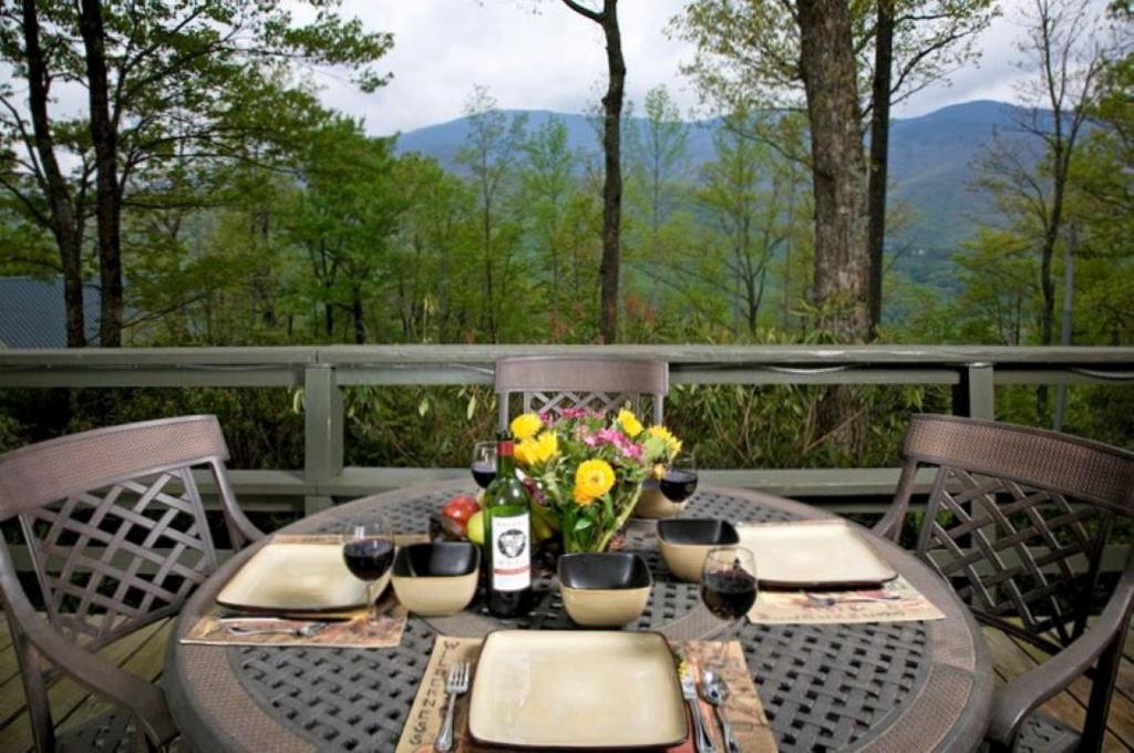 a table with flowers and wine glasses on a deck at Roaring Fork Chalet in Burnsville