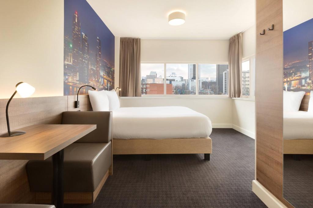 a hotel room with two beds and a desk and a window at Rotterdam Teleport Hotel in Rotterdam