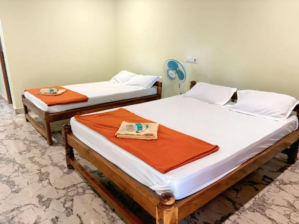 two beds in a room with orange sheets at Coco Beach Front Stay & Cafe in Gokarna