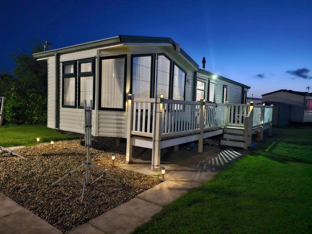 a tiny house with a porch and lights in a yard at V10 static caravan in Ingoldmells