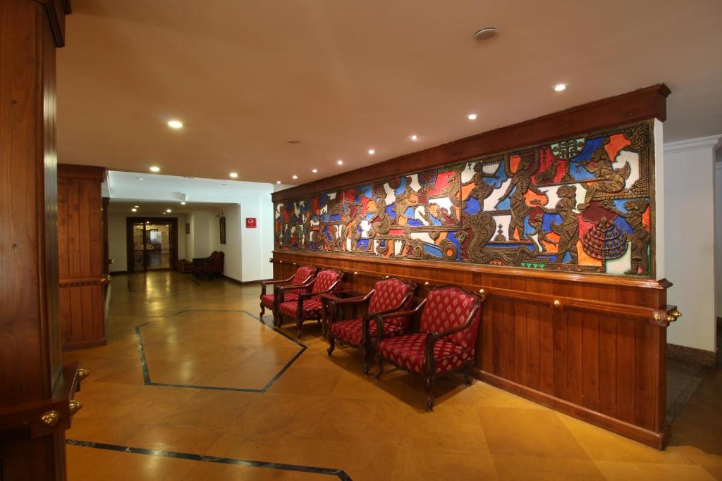 a lobby with chairs and a large painting on the wall at Sopanam Heritage in Guruvāyūr