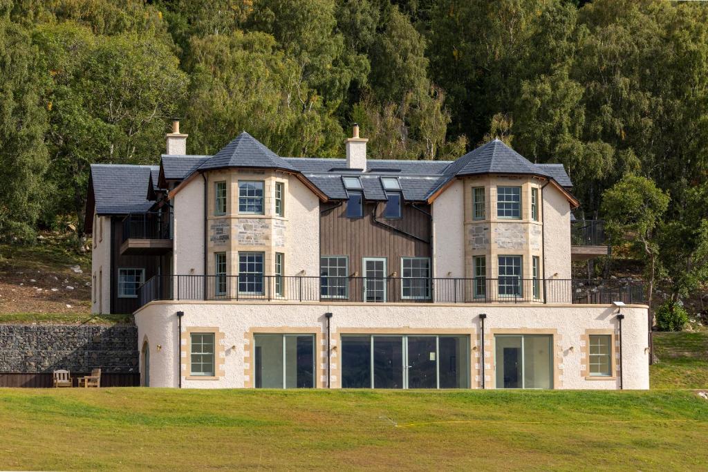 a large house on top of a grass field at Schiehallion House in Pitlochry
