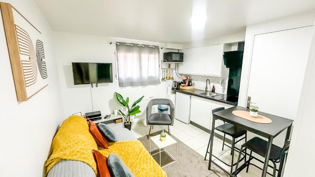 a living room with a couch and a table and a kitchen at La Parenthèse Urbaine - T2 Cosy et fonctionnel - Metro 5 Bobigny in Bobigny