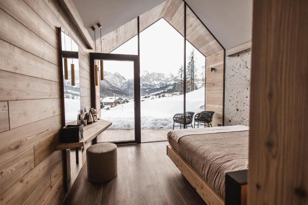 a bedroom with a bed and a large window at Borgo Antico Mountain Lodge in Sappada