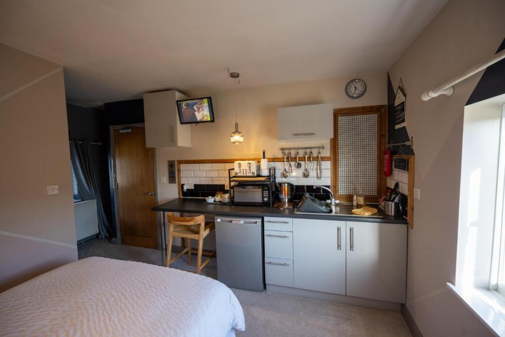 a kitchen with white cabinets and a bed in a room at Willow Studio in Telford