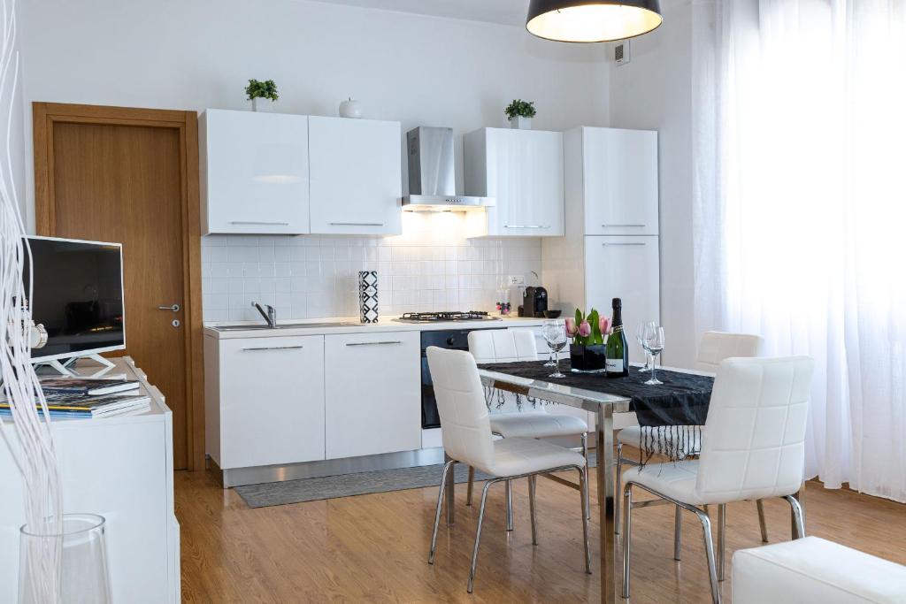 a kitchen with white cabinets and a table and chairs at Lizard Residence in Lido di Jesolo