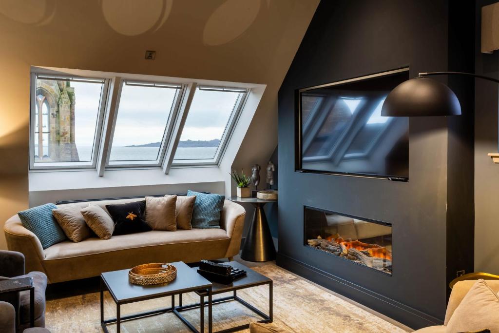 a living room with a couch and a fireplace at Arran Shores Luxury Shorefront Penthouse Suite 10 in Lamlash