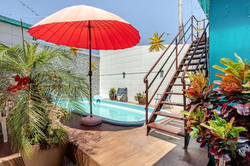 a red umbrella next to a pool with a staircase at Apartamento Canoas 2 quartos in Canoas