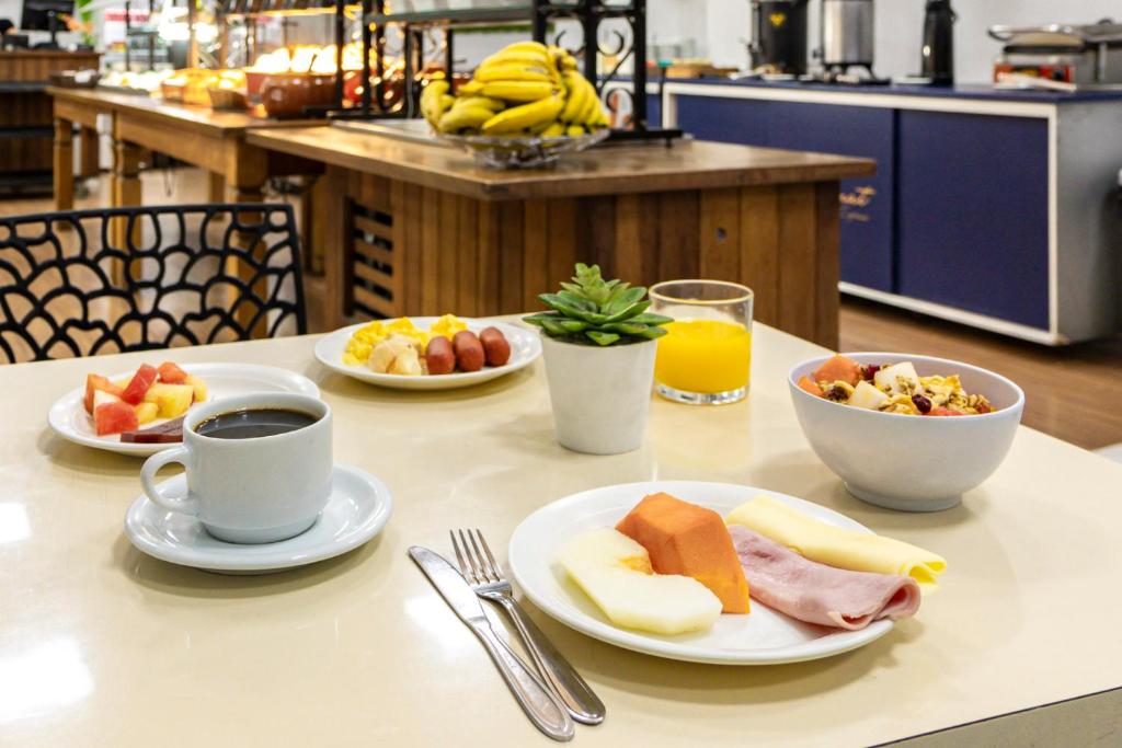 a table with plates of food and cups of coffee at Travel Inn Express Hotels Brás in São Paulo