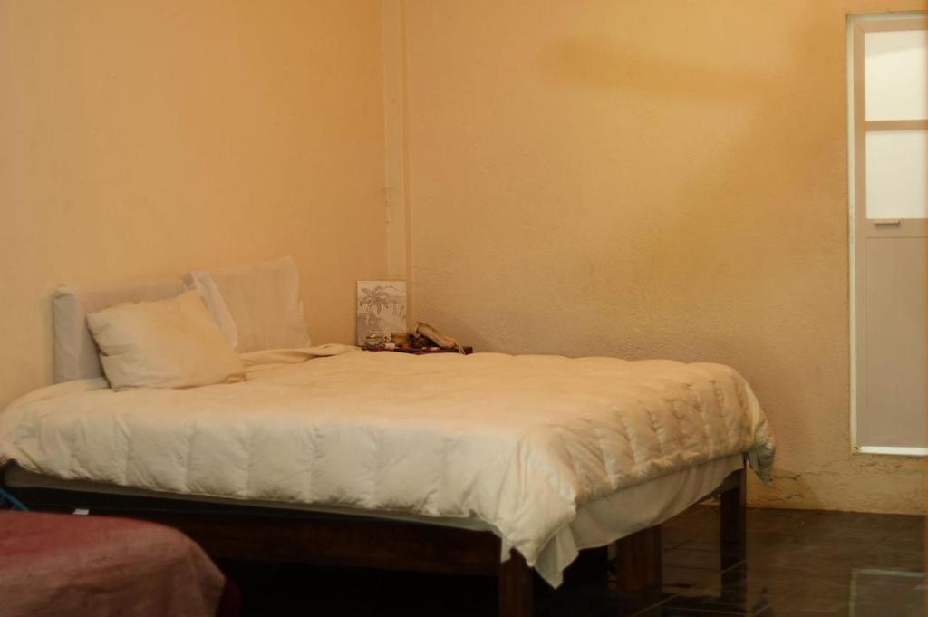 a bed with white sheets and pillows in a room at El jardin in Brisas de Zicatela