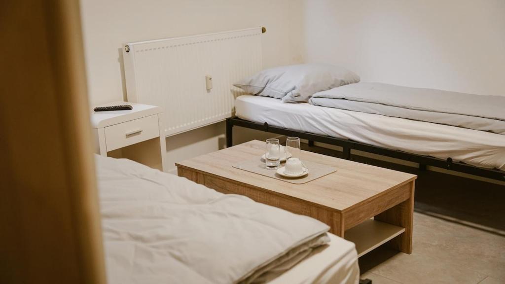 a room with two beds and a table with glasses on it at Zentrales Apartment Lichtenfels in Lichtenfels