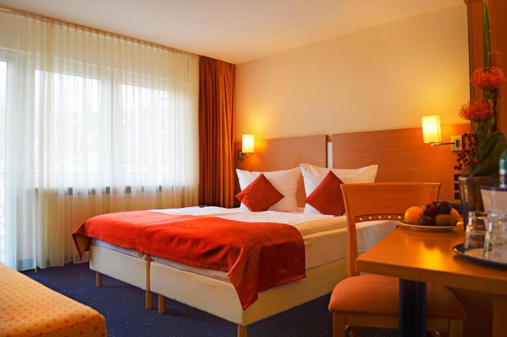 um quarto de hotel com uma cama com um cobertor vermelho em Hotel Plaza em Frankfurt am Main