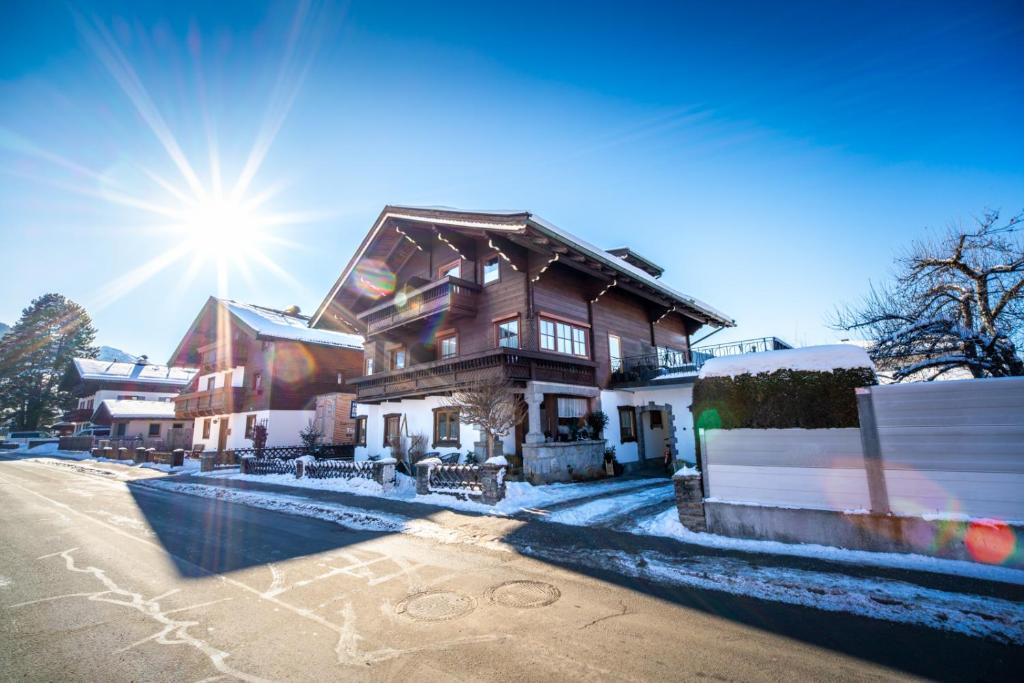 a house in the snow with the sun behind it at Pension Kuntschner in Mittersill