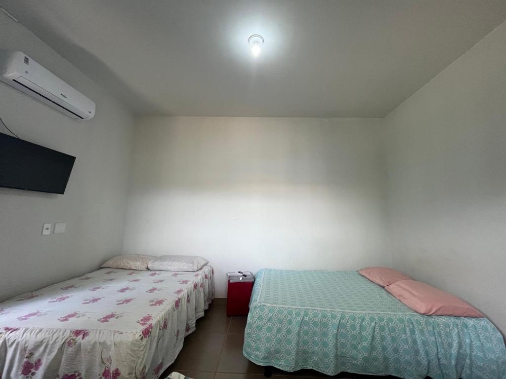 a room with two beds and a tv in it at Residencial Jasmim quarto Standard 01 in Palmas