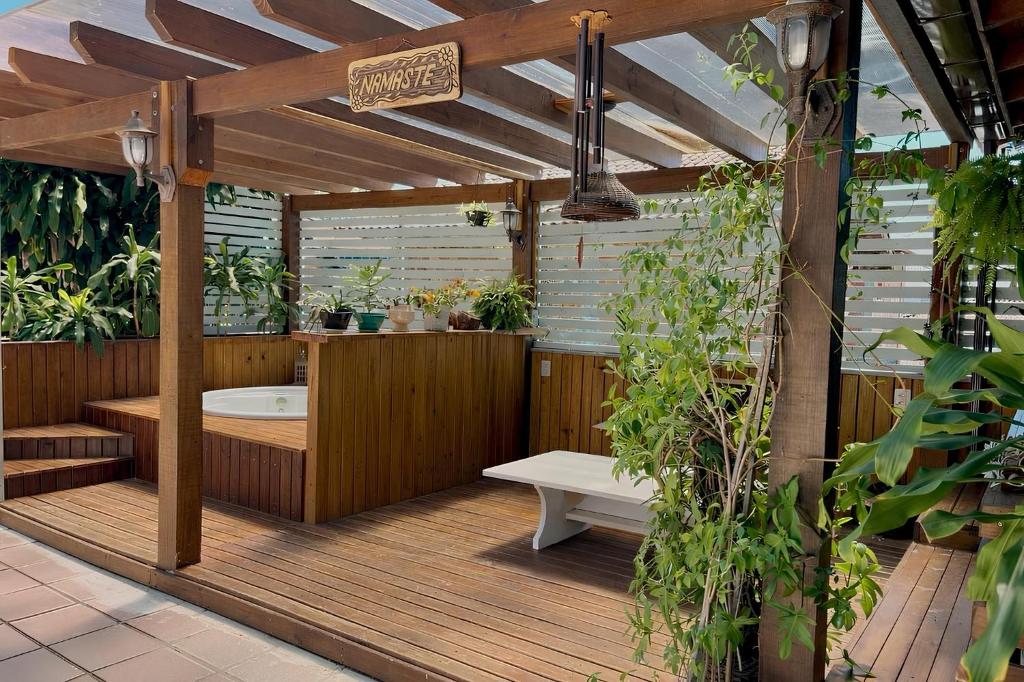 a wooden deck with a bath tub with plants at Hostel House Santinho in Florianópolis