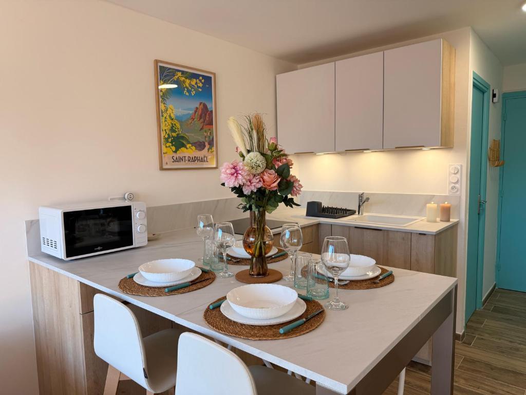 a kitchen with a table with plates and flowers on it at Le Petit Bleu Studio - Boulouris in Saint-Raphaël