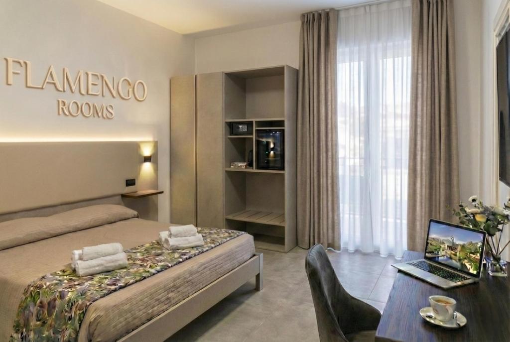 a hotel room with a bed and a desk with a laptop at Flamengo rooms in Centola