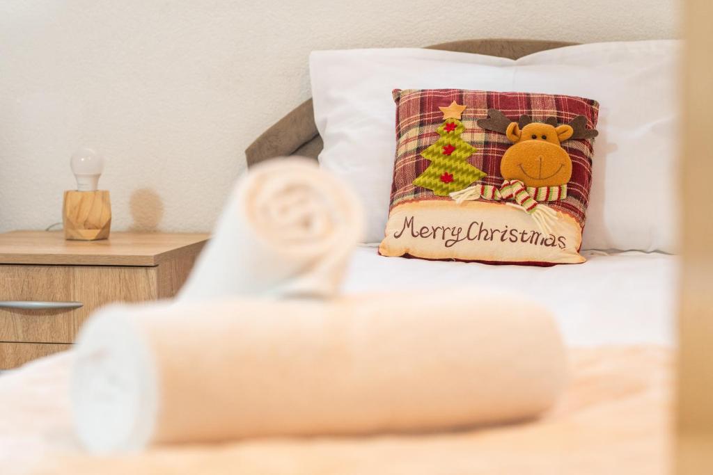 a bed with a merry christmas pillow on it at Our House Apartments in Kolašin