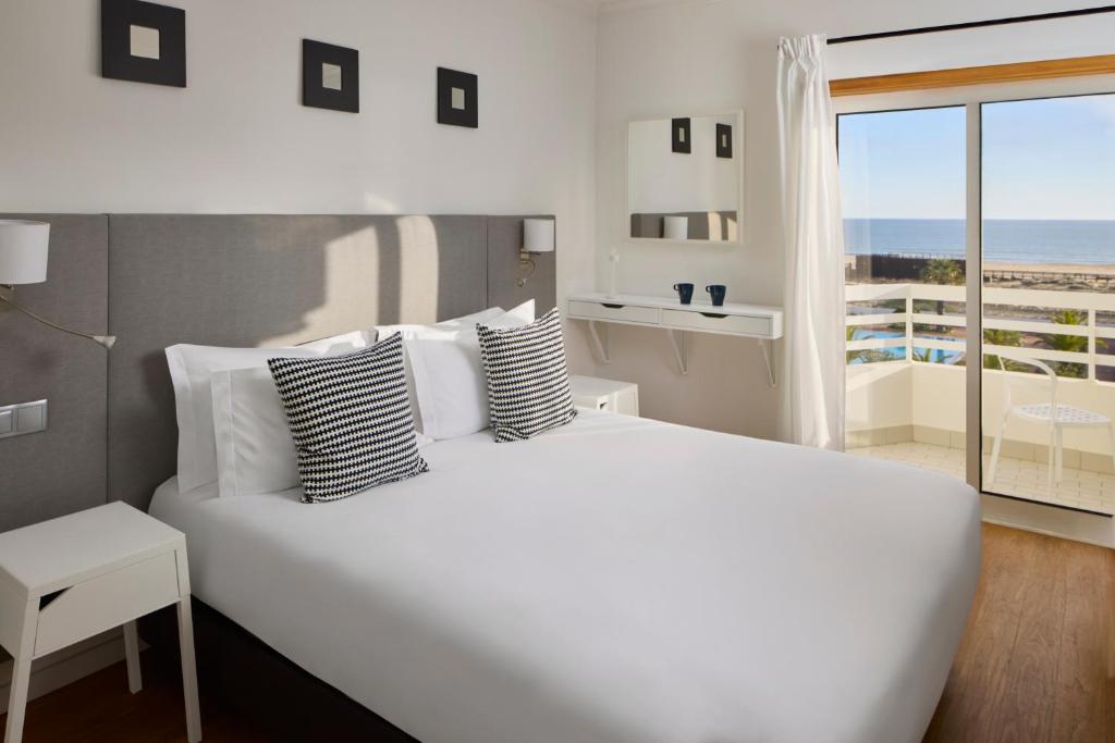 a bedroom with a large white bed with a view of the ocean at Monte Gordo Prestige Apartments in Monte Gordo