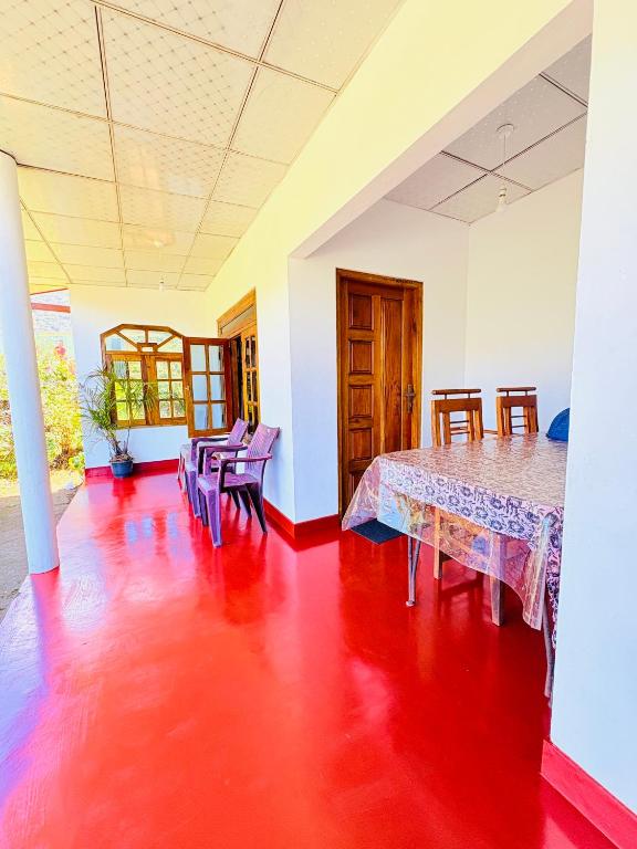 a room with a red floor and a table and chairs at GREENISH INN (ROOMS) in Nanu Oya